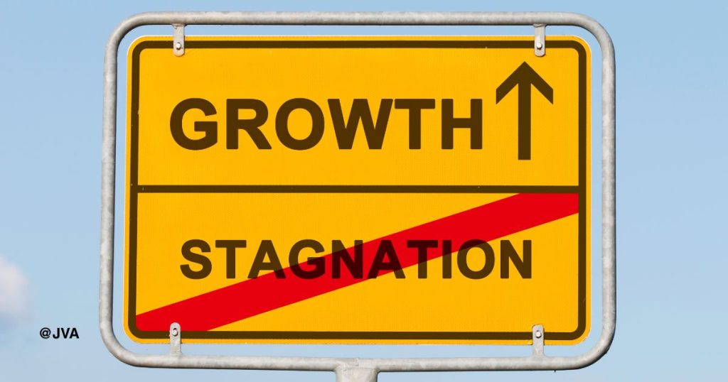 Sebuah papan penunjuk arah berwarna kuning dengan tulisan 'GROWTH' tanda panah lurus dan tulisan "STAGNATION" yang disilang merah.